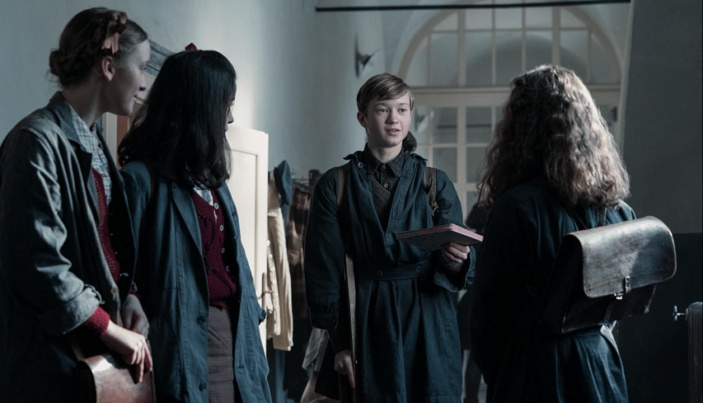 a boy in a robe holding a book and standing next to a group of people